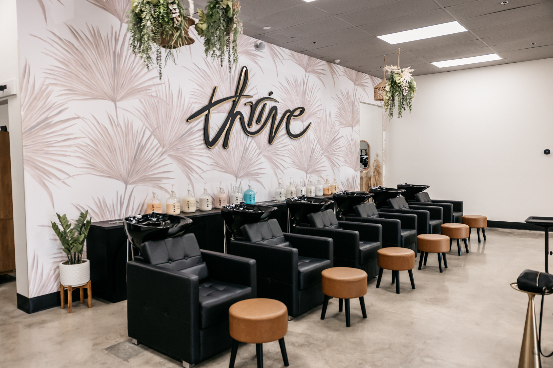 Salon Thrive interior — the 'thrive' script wall behind stylist stations
